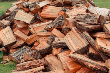 Firewood is stacked in autumn. Chopped pile of wood. Lots of wood from logs. Preparation of firewood for the winter. background texture pattern with stacked dry chopped firewood. Trees in the sawmill