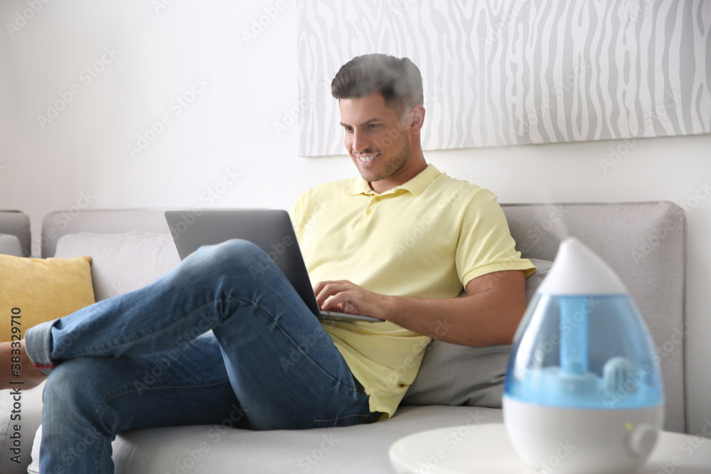 Sticker man using laptop in room with modern air humidifier