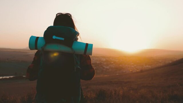 Woman traveler with backpack hiking in mountains. Silhouette hiker walking in the mountains, freedom and happiness, achievement in mountains. Active sport lifestyle concept.