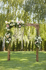 beautiful arch for the wedding ceremony decorated with flowers in sunny summer day outside