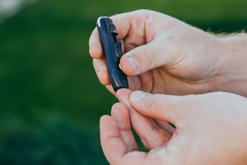 Man taking a blood sample with a lancet handle outside. Diabetes concept