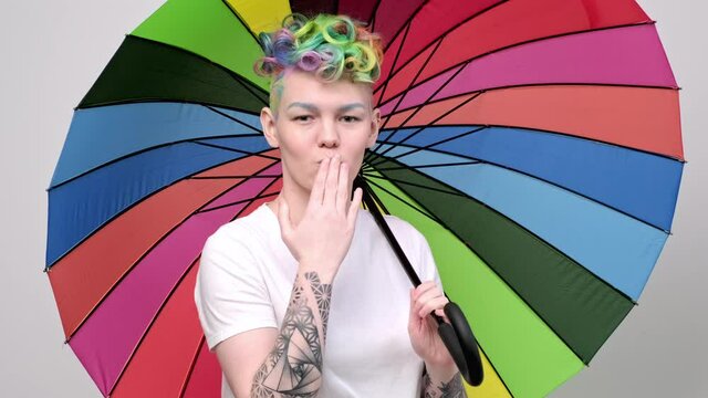 Beautiful young girl with dyed hair and a short haircut. Opens a bright colored umbrella and twists it in front of the camera.