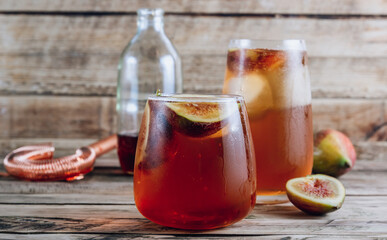 Cold lemonade cocktail with figs on rustic wooden background. Selective focus