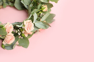 Wreath made of beautiful flowers on pink background, space for text