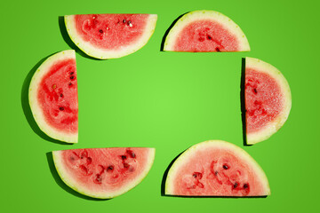 Frame of watermelon slices on green background, flat lay. Space for text