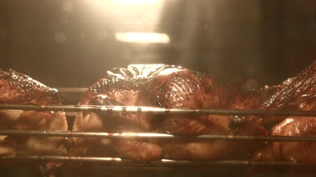 Close up on a grilled chicken hanging on a dirty broiler