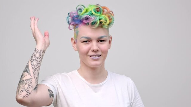 A young girl with a short haircut and oxen painted in the colors of the rainbow. Multicolor dyeing. Poses against a white background in a white T-shirt.