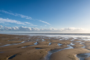 Muster im Sand bei Ebbe mit Wolkenband am Horizont