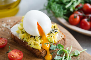 Breakfast avocado and egg toast garnished with sesame seeds and micro greens. Closeup view