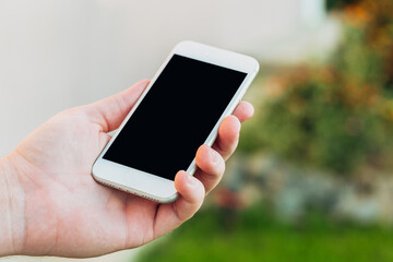 close-up shot of male hands holding smartphone with blank screen copy space for your text message or information content, against green nature background