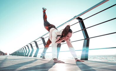 outdoor workout concept. young woman in tracksuit performs sports workout on the pier