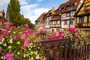 View on Colmar town with half-timbered traditional houses by the bank of the canal, flowers on the bridge. Summertime , Alsace France.