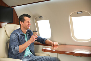 Handsome man with paper cup on plane. Air travel