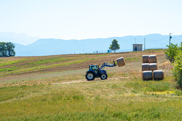 Obraz premium Hay is stacked by the tractor. Work in the countryside.