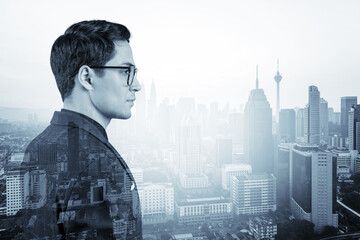 Young handsome businessman in suit and glasses dreaming about new career opportunities after MBA graduation. Kuala Lumpur on background. Double exposure.