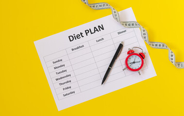 Diet schedule planner, measuring tape, pen and alarm top view