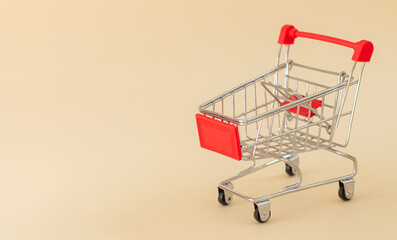 Empty red shopping cart or trolley on beige background