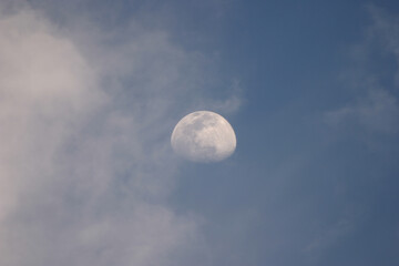 Naklejka na ściany i meble moon behind clouds in blue sky