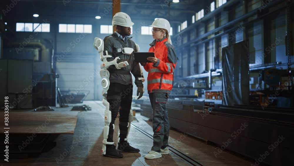 Leinwandbilder Engineer and Manual Labor Worker in a Bionic Exoskeleton Prototype Check Development Test Results on a Tablet. Heavy Industry Factory Engineers Discuss Warehouse Work and Futuristic Technology. 