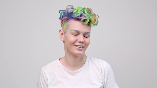 A young girl with a short haircut and oxen painted in the colors of the rainbow. Multicolor dyeing. Poses against a white background in a white T-shirt.