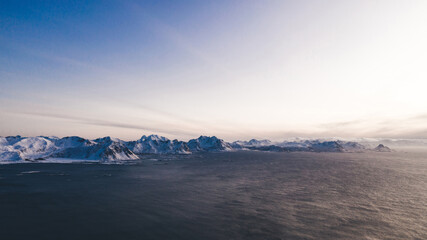 Breathtaking bird's eye view of majestic fjord mountains covered with snow in winter. Aerial view of scenery rock peaks, picturesque beautiful nature landscape. Lofoten Island surrounds by Nordic sea
