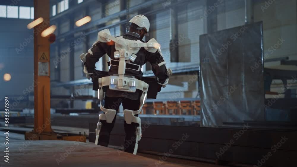 Poster black african american engineer is testing a futuristic bionic exoskeleton and picking up metal obje