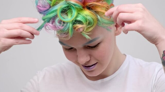 A young girl with a short haircut and oxen painted in the colors of the rainbow. Multicolor dyeing. Poses against a white background in a white T-shirt.