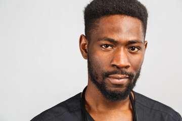Obraz premium close-up portrait of a happy African doctor in black medical uniform on a gray background.