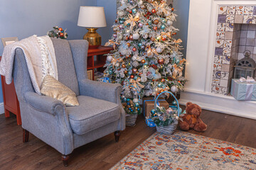 Classic Christmas decorated interior room, New year tree with silver decorations. Modern blue classical style interior design apartment with fireplace and armchair. Christmas eve at home.