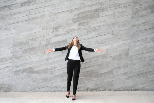 Youthful happy business woman in black suit arms wide open and raised in the air. High quality photo