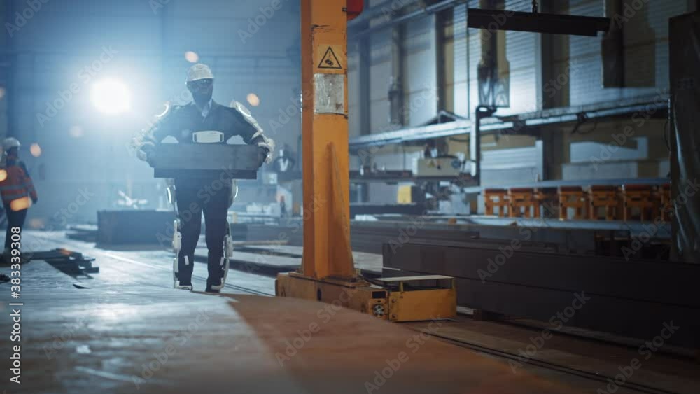 Poster black african american engineer is testing a futuristic bionic exoskeleton and picking up metal obje