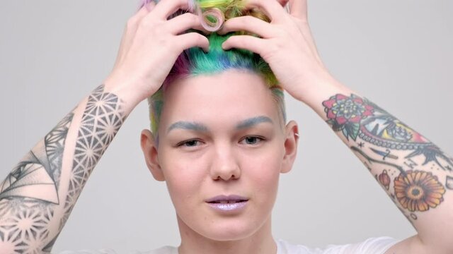 A young girl with a short haircut and oxen painted in the colors of the rainbow. Multicolor dyeing. Poses against a white background in a white T-shirt.