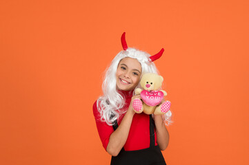 this is for me. teen girl ready to celebrate costume party. funny red imp horns. happy halloween. smiling child in devil horns with teddy bear toy. kid has white hair wig. childhood happiness