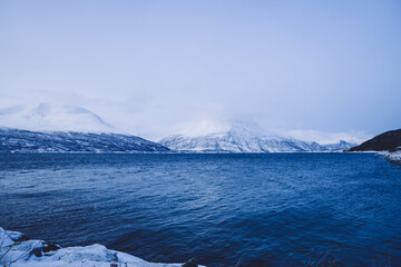 Picture of scenic winter cold scandinavian view of mountains with snow peaks near lake, beautiful nature landscape of landmark fjords on north