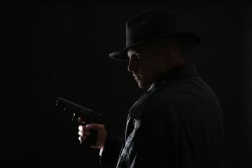 Old fashioned detective with gun on dark background