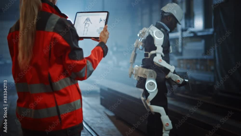 Fototapete female engineer is testing vital components of a futuristic bionic exoskeleton that her project assi