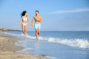 Fototapeta premium Happy young couple running together on beach