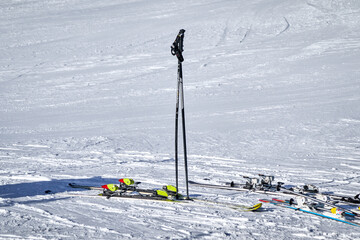 Ski poles are stuck in the snow and skis are next to them