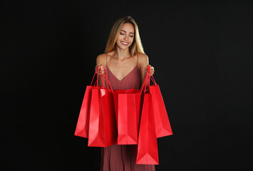 Fototapeta na wymiar Happy young woman with shopping bags on dark background. Black Friday Sale