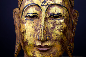 Fototapeta na wymiar Close up of isolated ancient gold paint wood Buddha head face of thai statue in buddhist temple