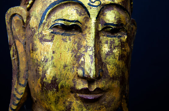Close up of isolated ancient gold paint wood Buddha head face of thai statue in buddhist temple