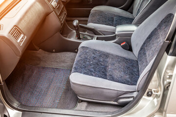 Comfortable front seats and steering wheel inside the car: the driver and passenger, tied with gray velourus, modern interior design.