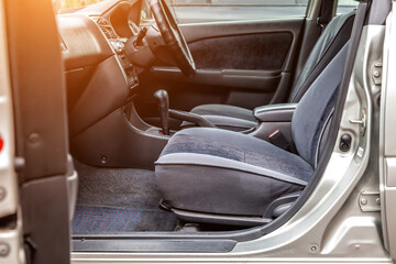 Comfortable front seats and steering wheel inside the car: the driver and passenger, tied with gray velourus, modern interior design.