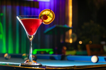 Soft focus and Closeup glass of cosmopolitan cocktail decorated with on the snooker table at bar background.