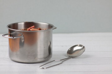 a saucepan of soup and soup ladle on white wooden background