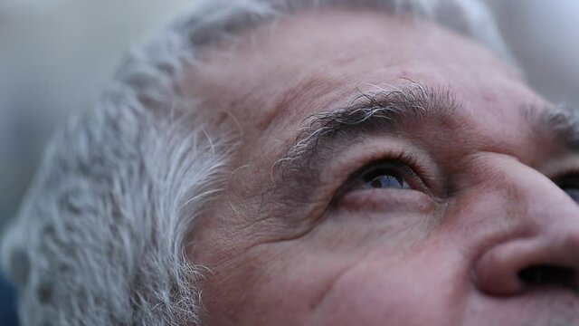 Senior man opening eyes looking at sky with hope and faith