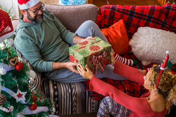 Gifts share and giving action at home with happy adult couple in happy christmas holiday eve day...