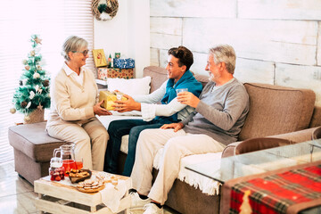 Obraz premium Caucasian family sharing gifts each other from grandfathers to grandson - senior to old generations together having fun in christmas holidays at home giving gift and enjoying the celebration