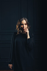 Girl in black dress in studio black wall