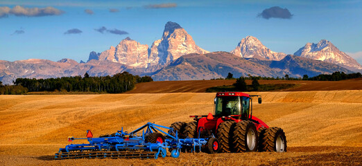 Tractor Farming Ground Harvesting Crops in Fall Autumn Teton Mountains Rugged with Moon